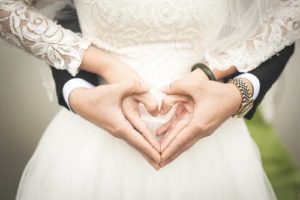 A picture of a couple making a double heart with their hands.